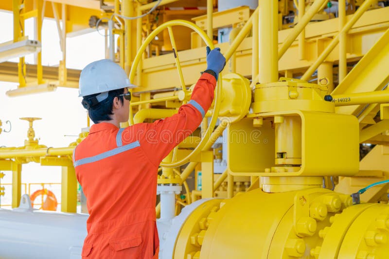 Operatore di produzione apre la valvola manuale a sfere del sistema di trattamento del petrolio e del gas per controllare la qual immagine stock libera da diritti Operatore di produzione apre la valvola manuale a sfere del sistema di trattamento del petrolio e del gas per controllare la qual immagine stock libera da diritti