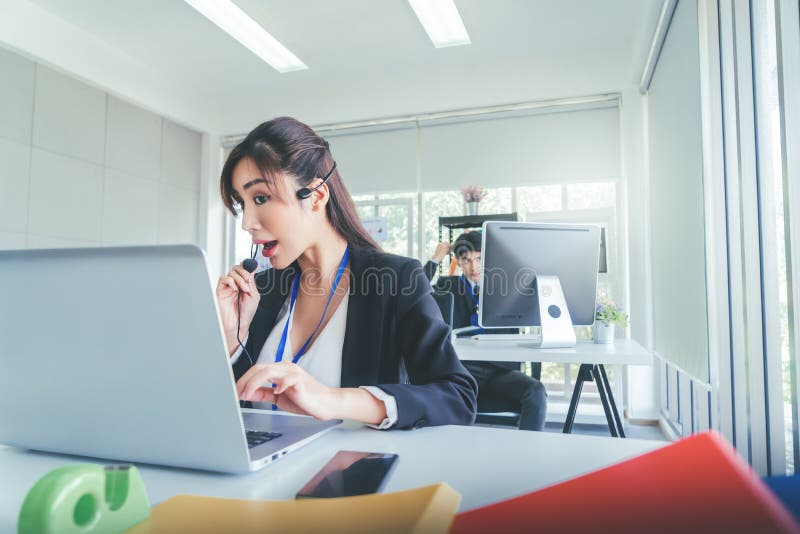Operators in Call center service talking to customer on the headphone while working on laptop for customer support royalty free stock image