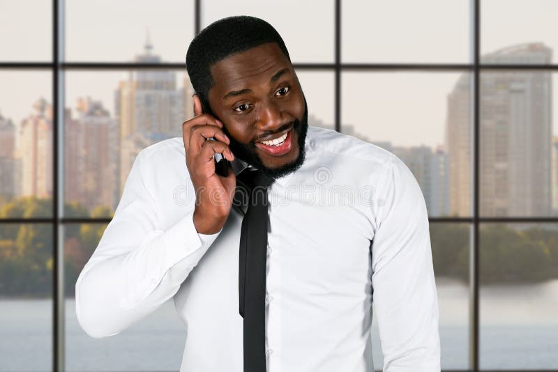 Opgewekt darkskinned cellphone van de kerelholding royalty-vrije stock afbeelding Opgewekt darkskinned cellphone van de kerelholding royalty-vrije stock afbeelding