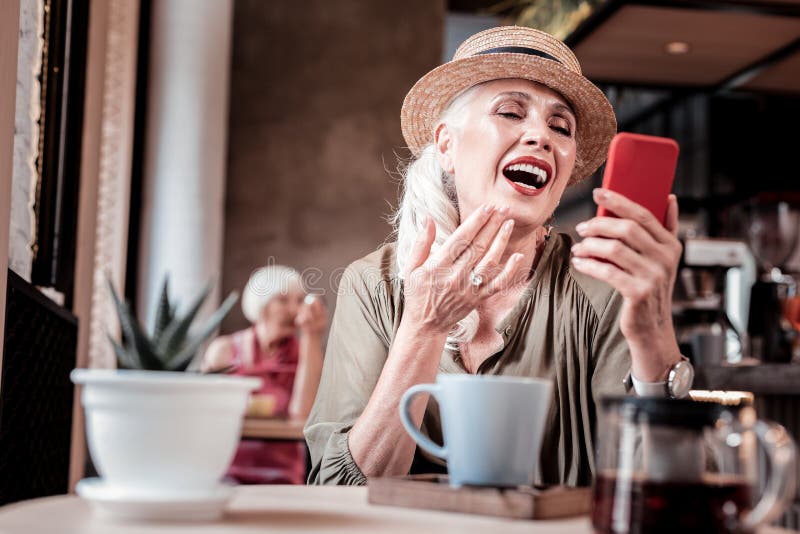 Opgewekte knappe oude vrouw die terwijl het hebben van gesprek lachen royalty-vrije stock afbeelding Opgewekte knappe oude vrouw die terwijl het hebben van gesprek lachen royalty-vrije stock afbeelding