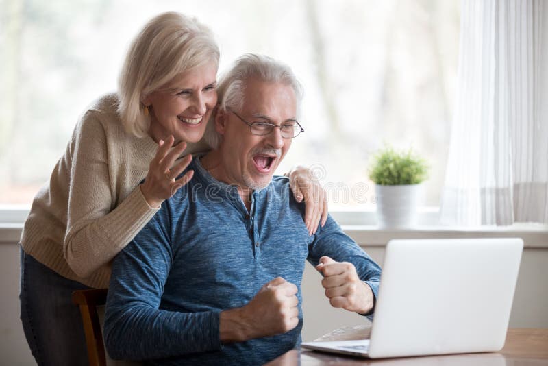 Opgewekte oude vrouw en echtgenoot die op het computerscherm kijken