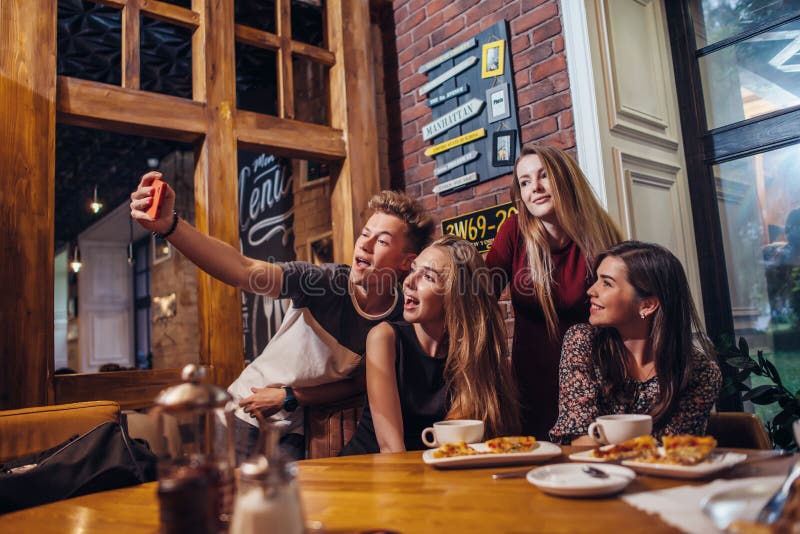 Opgewekte vrienden die selfie met smartphone uit zitting bij lijst nemen die nacht hebben royalty-vrije stock afbeelding Opgewekte vrienden die selfie met smartphone uit zitting bij lijst nemen die nacht hebben royalty-vrije stock afbeelding