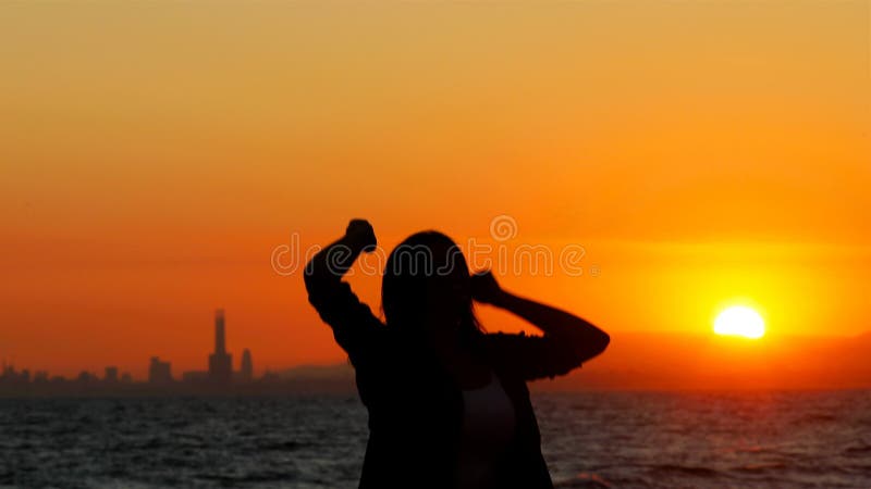 Opgewekte vrouw die bij zonsondergang het vieren succes springen