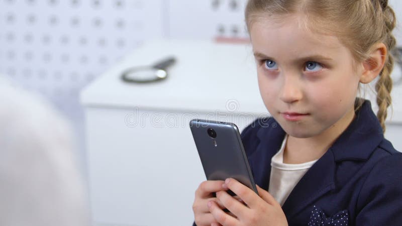 Ophthalmologist trying to take smartphone from girl hands, gadget addiction