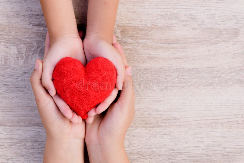 Health care, love, organ donation, family insurance and CSR concept. adult and child hands holding handmade red heart on wooden background. Health care, love, organ donation, family insurance and CSR concept. adult and child hands holding handmade red heart on wooden background.