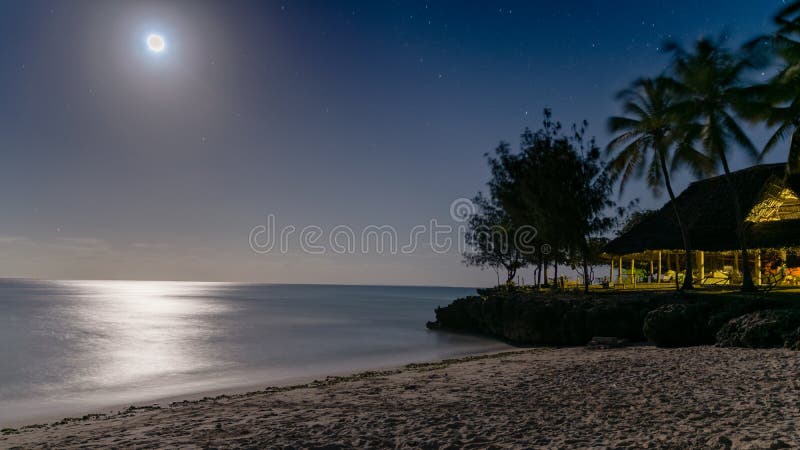 Opinião bonita da noite de uma praia do paraíso da com o fulgor de prata do luar que reflete fora da água foto de stock royalty free Opinião bonita da noite de uma praia do paraíso da com o fulgor de prata do luar que reflete fora da água foto de stock royalty free