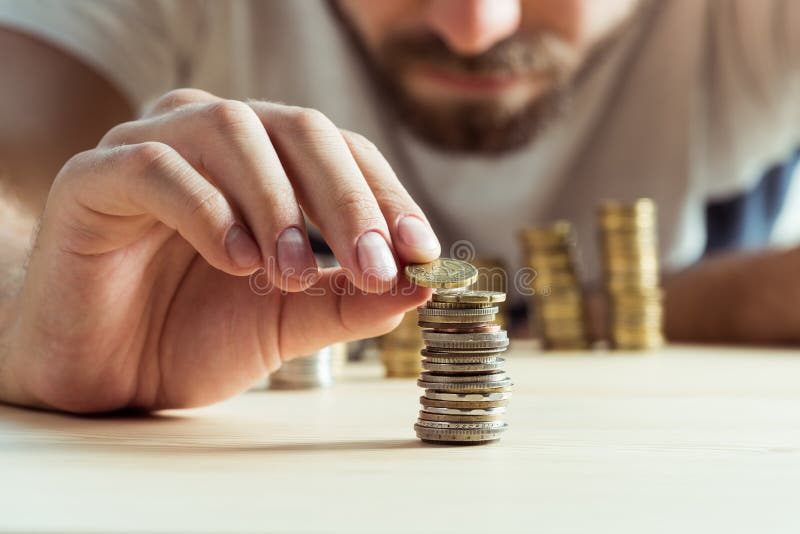Opinião colhida o homem que empilha moedas na tabela imagens de stock Opinião colhida o homem que empilha moedas na tabela imagens de stock