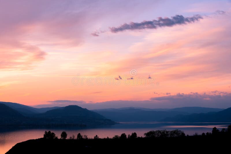 Opinião da noite do céu do por do sol sobre o lago com as silhuetas das montanhas e das árvores fotos de stock Opinião da noite do céu do por do sol sobre o lago com as silhuetas das montanhas e das árvores fotos de stock