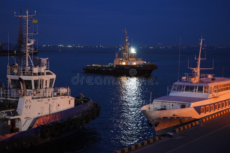 Opinião da noite do rebocador no porto da carga de Odessa Os reboquees e um guindaste de flutuação estão no porto Panorama da noi imagem de stock royalty free Opinião da noite do rebocador no porto da carga de Odessa Os reboquees e um guindaste de flutuação estão no porto Panorama da noi imagem de stock royalty free