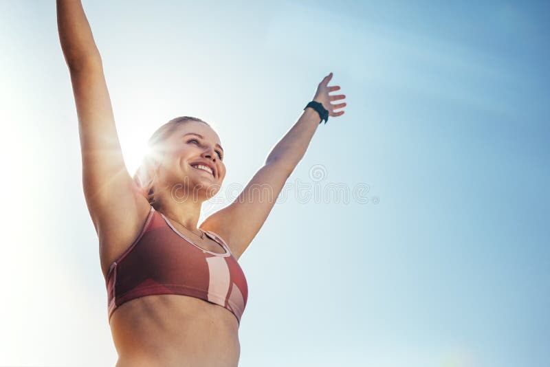 Opinião de baixo ângulo um atleta fêmea que está fora com o sol no fundo Mulher da aptidão que faz o exercício fora com claro