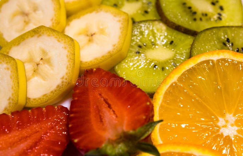 Opinião do close-up em frutos tropicais: banana, quivi, laranja, e morangos foto de stock Opinião do close-up em frutos tropicais: banana, quivi, laranja, e morangos foto de stock
