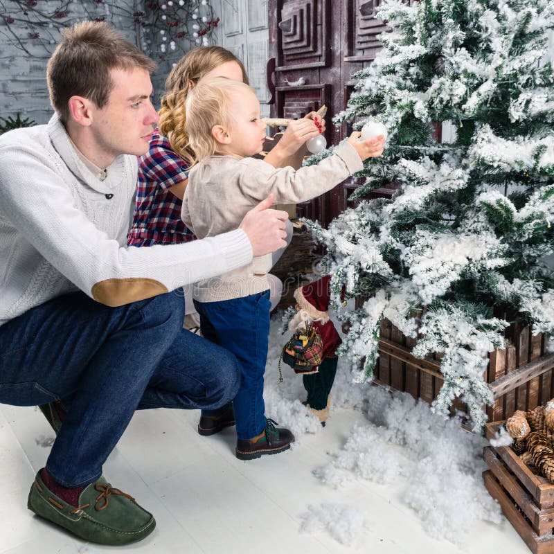 Opinião lateral a família feliz que decora a árvore de Natal em casa con imagem de stock Opinião lateral a família feliz que decora a árvore de Natal em casa con imagem de stock