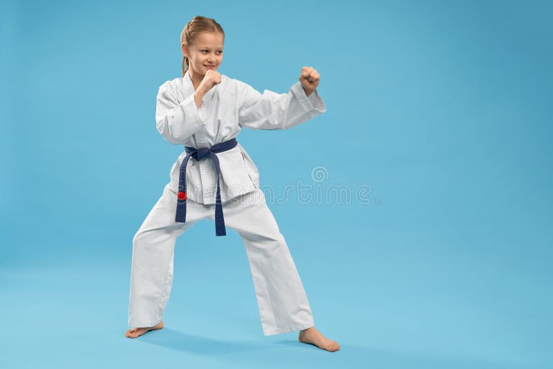 Opinião lateral a menina que faz artes marciais no fundo isolado fotos de stock Opinião lateral a menina que faz artes marciais no fundo isolado fotos de stock