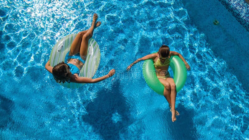 A opinião superior aérea as crianças na piscina de cima de, crianças felizes nada em anéis de espuma infláveis do anel e tem o di fotografia de stock A opinião superior aérea as crianças na piscina de cima de, crianças felizes nada em anéis de espuma infláveis do anel e tem o di fotografia de stock