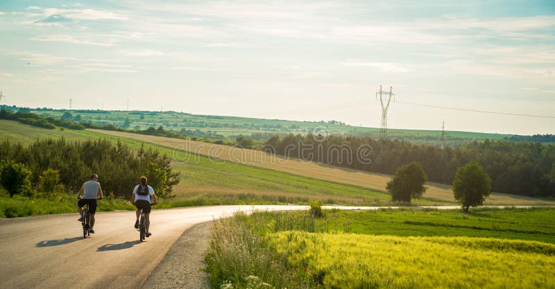 Opini?o traseira dois ciclistas que montam abaixo da estrada secund?ria atrav?s das montanhas Homens ocasionais que t?m o diverti fotografia de stock royalty free Opini?o traseira dois ciclistas que montam abaixo da estrada secund?ria atrav?s das montanhas Homens ocasionais que t?m o diverti fotografia de stock royalty free