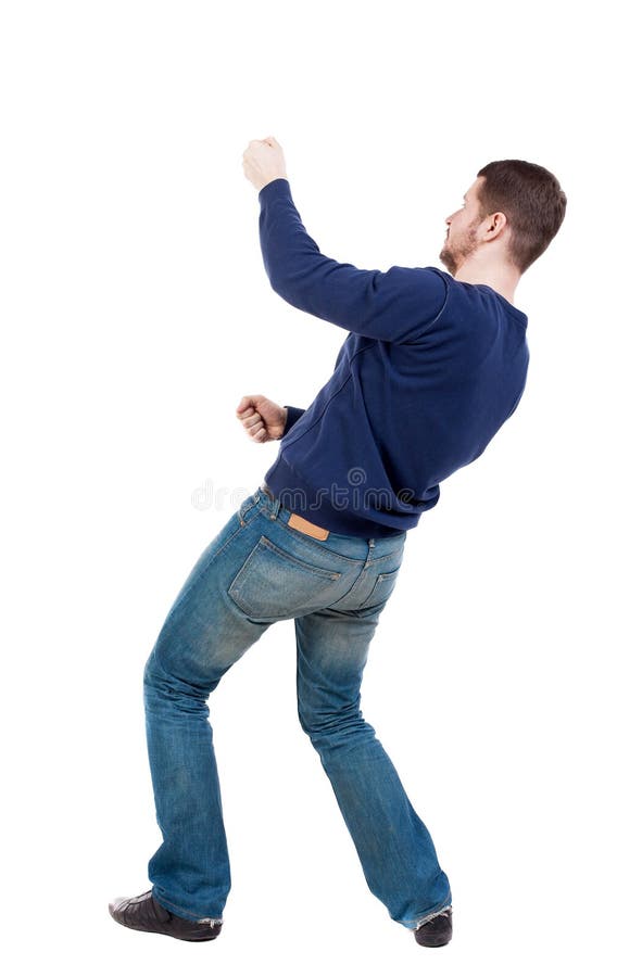 A opinião traseira o homem ereto que puxa uma corda da parte superior ou adere-se t foto de stock A opinião traseira o homem ereto que puxa uma corda da parte superior ou adere-se t foto de stock