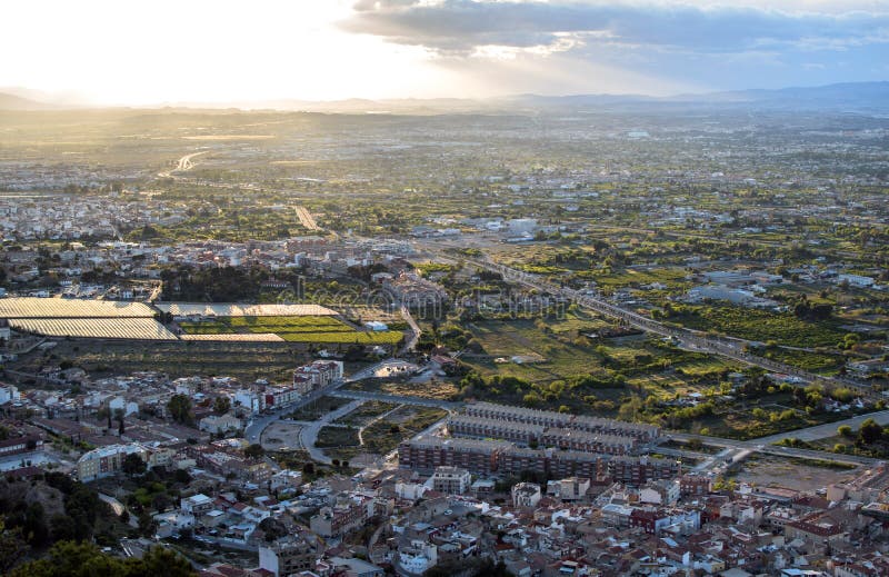 Opinión aérea del paisaje urbano de la ciudad de Murcia, de las montañas durante una puesta del sol hermosa fotografía de archivo Opinión aérea del paisaje urbano de la ciudad de Murcia, de las montañas durante una puesta del sol hermosa fotografía de archivo