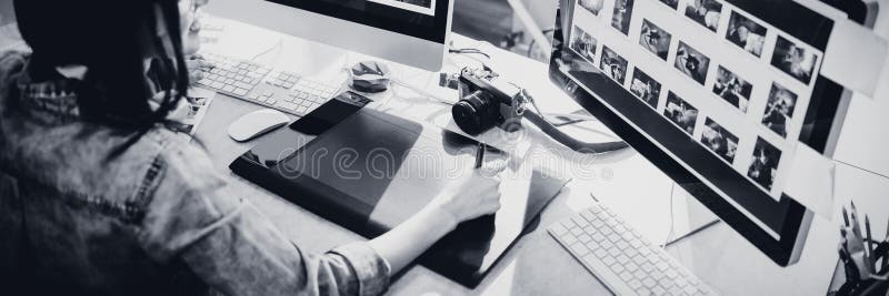 High angle view of female graphic designer using tablet while working on computer at office. High angle view of female graphic designer using tablet while working on computer at office