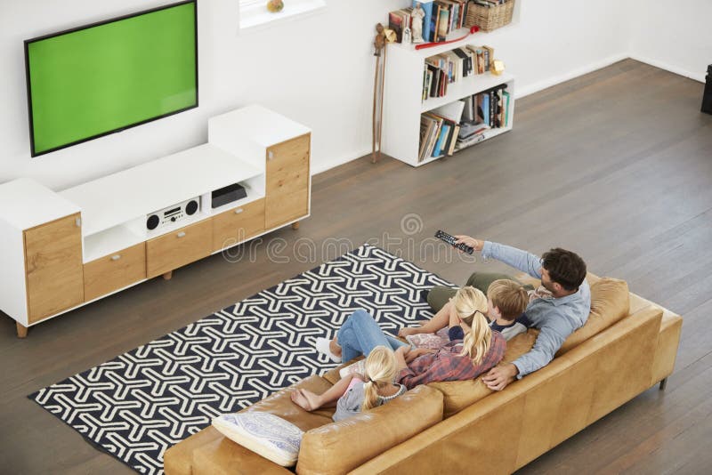 Opinión de alto ángulo la familia que se sienta en Sofa In Lounge Watching TV imagen de archivo libre de regalías