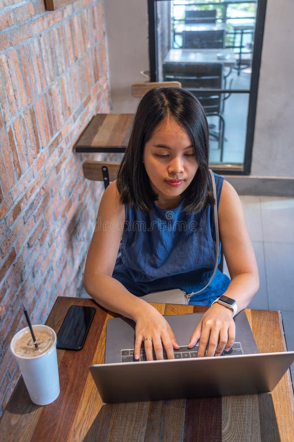 Opinión de alto ángulo la mujer que usa el ordenador portátil en el café rústico fotografía de archivo libre de regalías Opinión de alto ángulo la mujer que usa el ordenador portátil en el café rústico fotografía de archivo libre de regalías