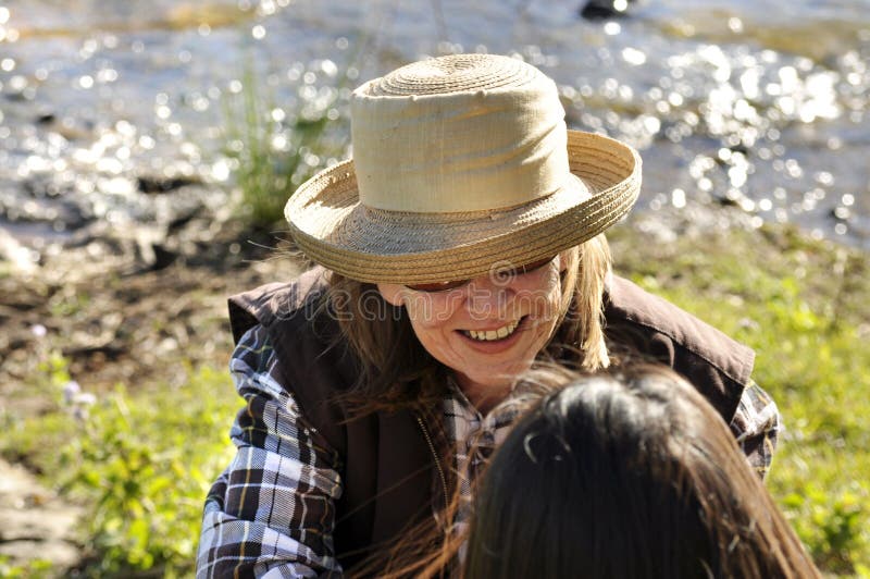 A simple candid portrait taken from overhead view of an attractive middle-aged woman deep in conversation with her friend , sitting beside the lake and smiling. A simple candid portrait taken from overhead view of an attractive middle-aged woman deep in conversation with her friend , sitting beside the lake and smiling.