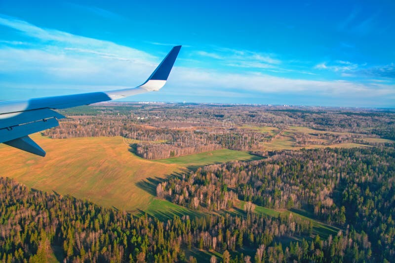 Opinión de la ventana del aeroplano Visión desde la ventana en el bosque de la primavera, prados, cielo azul Vuelo del ala del ` imagenes de archivo Opinión de la ventana del aeroplano Visión desde la ventana en el bosque de la primavera, prados, cielo azul Vuelo del ala del ` imagenes de archivo