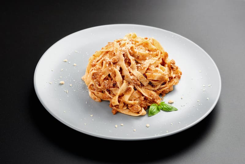 Opinión de ángulo bajo de los espaguetis boloñés con parmesano y albahaca púrpura, en un cuenco negro un fondo oscuro, fotografía de archivo libre de regalías Opinión de ángulo bajo de los espaguetis boloñés con parmesano y albahaca púrpura, en un cuenco negro un fondo oscuro, fotografía de archivo libre de regalías