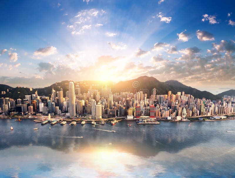 Opinión del horizonte de la ciudad de Hong Kong del puerto con los rascacielos y el sol