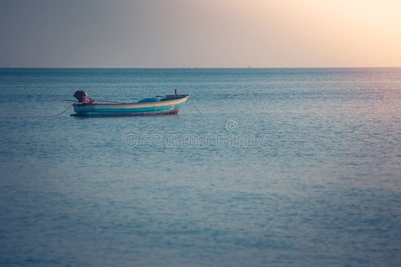 Opinión hermosa del paisaje marino del barco de pesca que flota en el mar con la luz de la puesta del sol en el fondo imagen de archivo Opinión hermosa del paisaje marino del barco de pesca que flota en el mar con la luz de la puesta del sol en el fondo imagen de archivo