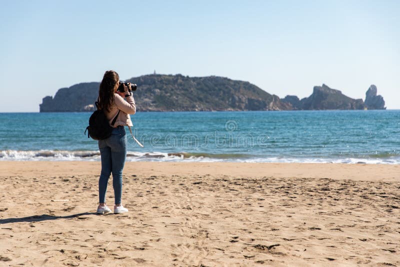 Opinión trasera la mujer que toma imágenes con la cámara de DSLR de las islas de la playa - islas de Medes fotografía de archivo Opinión trasera la mujer que toma imágenes con la cámara de DSLR de las islas de la playa - islas de Medes fotografía de archivo