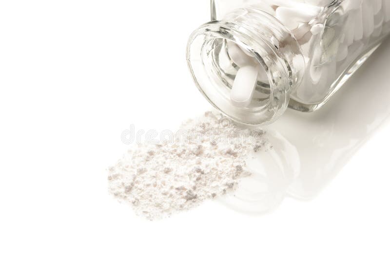 Closeup of an apothecary bottle on its side with a white powder from crushed pills spilling ou