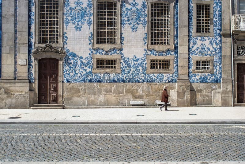 Oporto, Portogallo - 4 aprile 2017: La donna che cammina davanti ad una facciata piastrellata di Igreja fa Carmo nella P fotografia stock libera da diritti Oporto, Portogallo - 4 aprile 2017: La donna che cammina davanti ad una facciata piastrellata di Igreja fa Carmo nella P fotografia stock libera da diritti