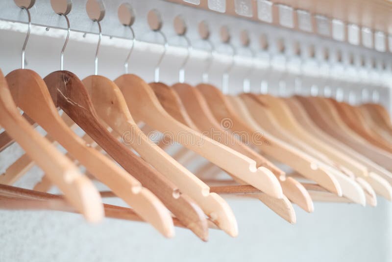 Stock of empty clothes hanger in wardrobe, wooden coat Hangers hanging on a cloth rail rack in closet hotel bedroom. Abstract for show of suits shop after clearance sales. Stock of empty clothes hanger in wardrobe, wooden coat Hangers hanging on a cloth rail rack in closet hotel bedroom. Abstract for show of suits shop after clearance sales.