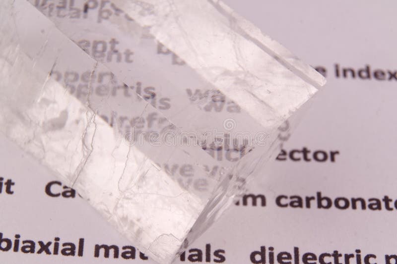 Optical birefringence demonstrated using a text using a natural double spar calcite crystal, macro shot and with real shadows