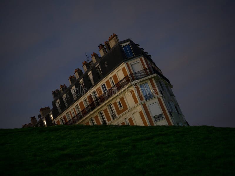 Optical illusion night panorama of historic old sinking house building at green grass hill Montmartre Paris France