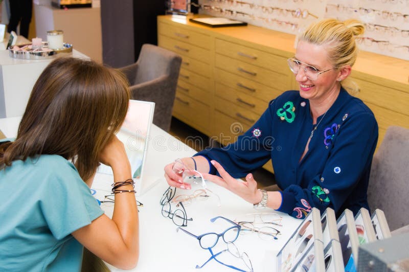 Optician salon saleswoman with her client choosing eyeglasses royalty free stock images Optician salon saleswoman with her client choosing eyeglasses royalty free stock images
