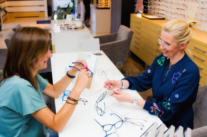 Optician salon saleswoman with her client choosing eyeglasses royalty free stock images Optician salon saleswoman with her client choosing eyeglasses royalty free stock images