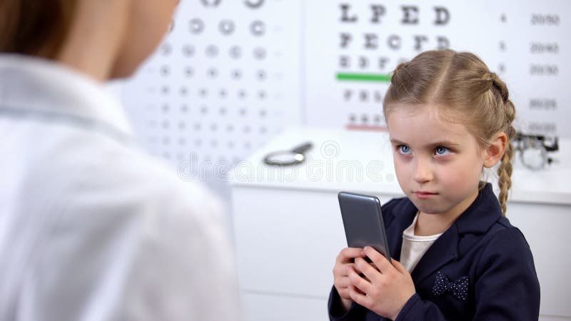 Optician trying to take cellphone from naughty child, video games damage sight stock photo Optician trying to take cellphone from naughty child, video games damage sight stock photo