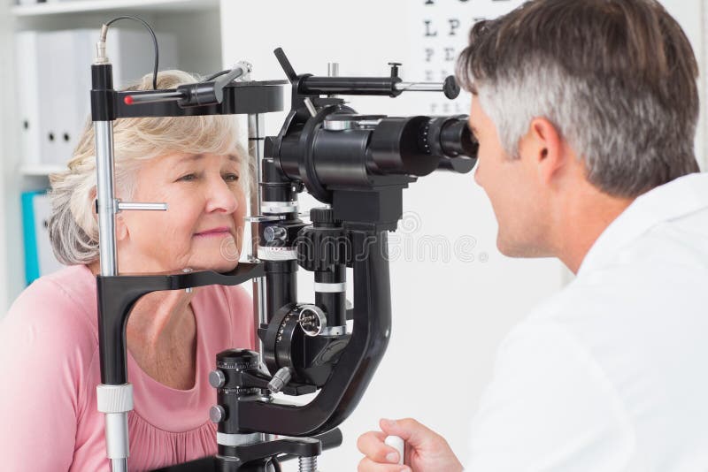 Optician рассматривая старшего женского пациента через разрезанную лампу стоковое фото Optician рассматривая старшего женского пациента через разрезанную лампу стоковое фото
