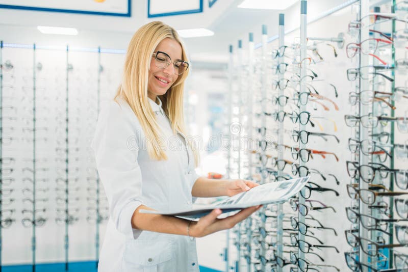 Opticien féminin avec le catalogue en verre dans des mains photo stock Opticien féminin avec le catalogue en verre dans des mains photo stock