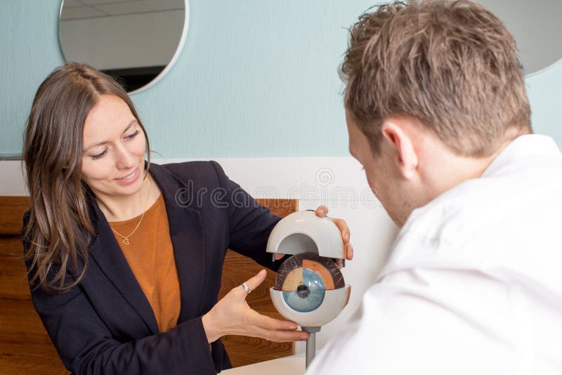 Opticien montrant un oeil à un client photographie stock Opticien montrant un oeil à un client photographie stock