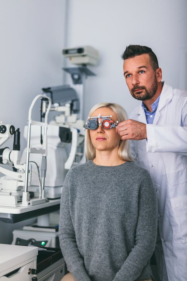 Optiker som kontrollerar patients synförmåga med försökramen fotografering för bildbyråer Optiker som kontrollerar patients synförmåga med försökramen fotografering för bildbyråer