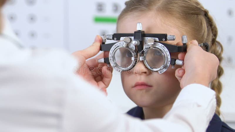 Optometrist examining girl eyesight using optical trial frame, vision checkup