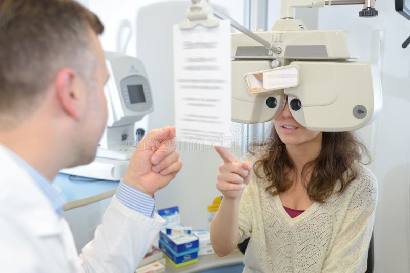 Optometrista maschile che esamina il giovane paziente con il phoropter fotografie stock libere da diritti