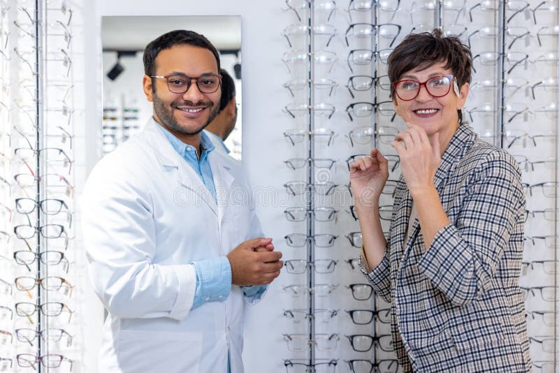 Optometrista maschio che aiuta una donna a scegliere gli occhiali immagini stock