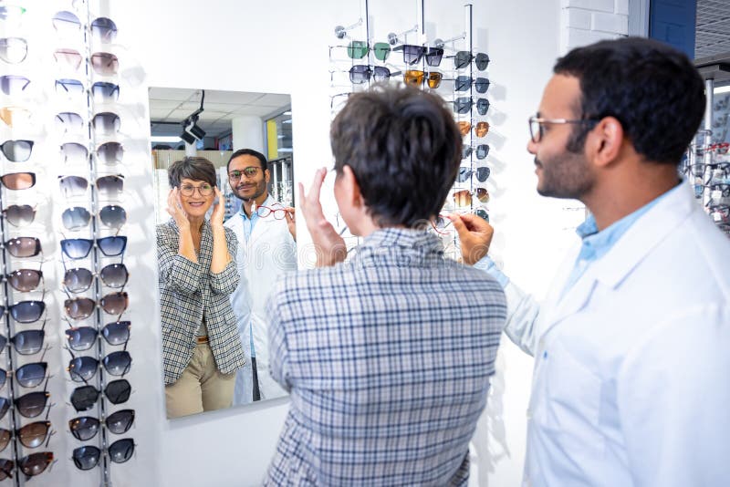 Optometrista maschio che aiuta una donna a scegliere gli occhiali fotografia stock libera da diritti