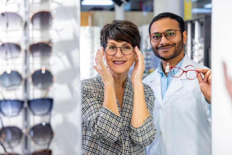 Optometrista maschio che aiuta una donna a scegliere gli occhiali fotografie stock libere da diritti