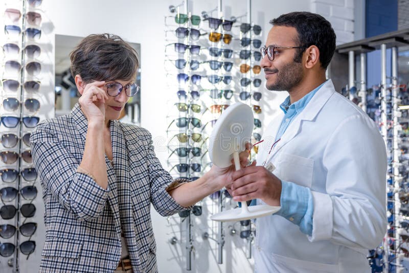 Optometrista maschio che aiuta una donna a scegliere gli occhiali immagine stock libera da diritti