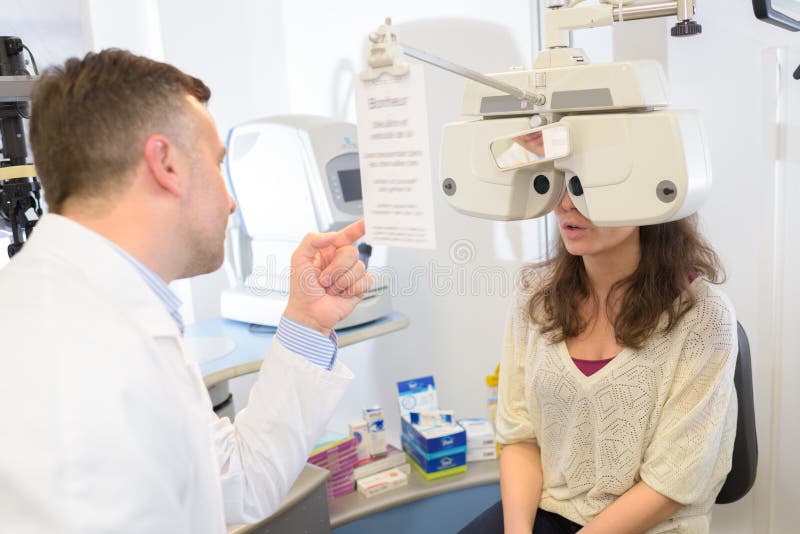 Optometrista maschio che effettua prove a vista per una paziente femmina fotografia stock