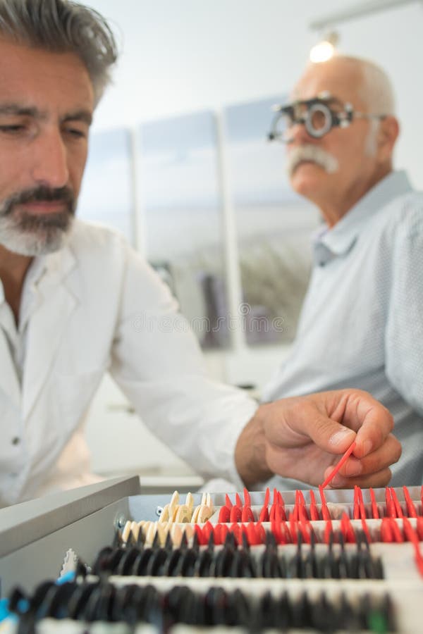 Optometrista maschio che esamina gli occhi senior dei pazienti immagine stock